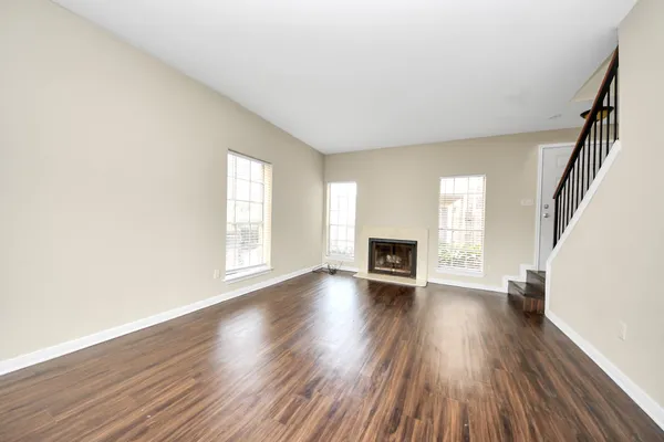 an empty room with wooden floor fireplace and windows