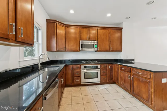 a large kitchen with stainless steel appliances granite countertop a stove a sink and a microwave