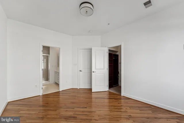 a view of an empty room with wooden floor and closet