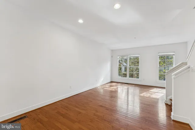 a view of an empty room with wooden floor and window