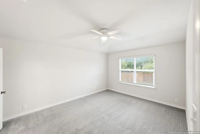 an empty room with a window and a fan