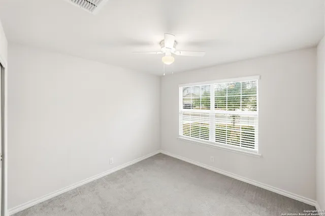 an empty room with windows and fan