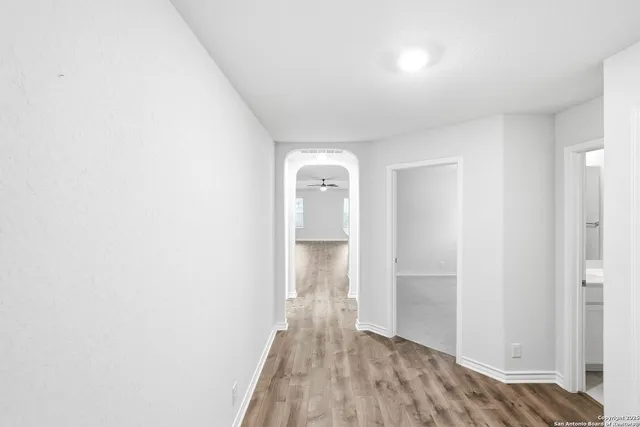 a view of hallway with walk in closet and wooden floor