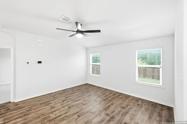 a view of empty room with wooden floor and fan