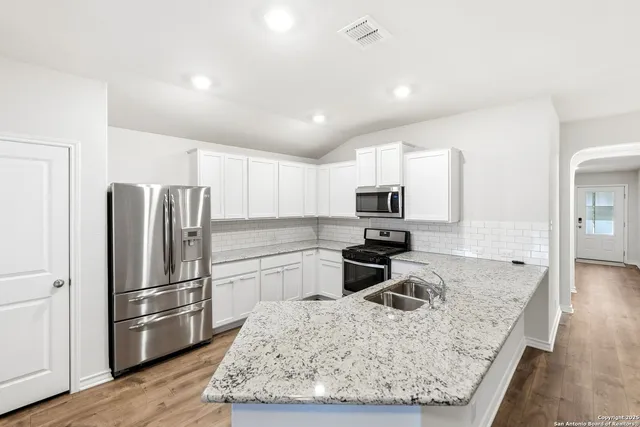 a kitchen with stainless steel appliances granite countertop a refrigerator sink and stove