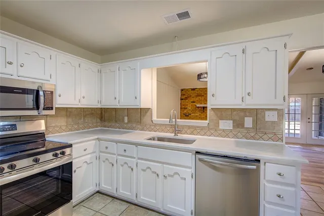 a kitchen with white cabinets appliances and a sink