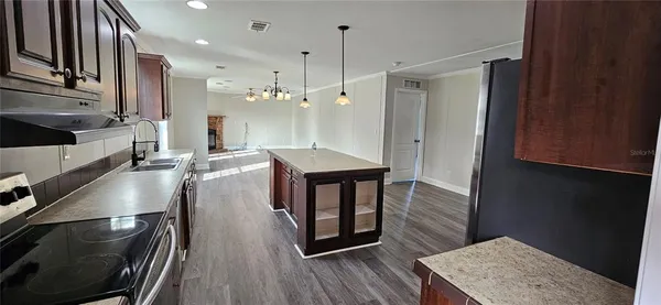 a kitchen with stainless steel appliances a sink a stove a refrigerator cabinets and wooden floor