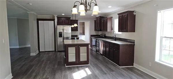 a kitchen with stainless steel appliances granite countertop a refrigerator a sink dishwasher a stove and white countertops with wooden floor