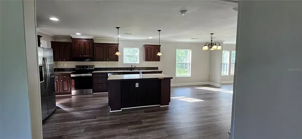 a kitchen with stainless steel appliances granite countertop a refrigerator a oven a sink and wooden cabinets