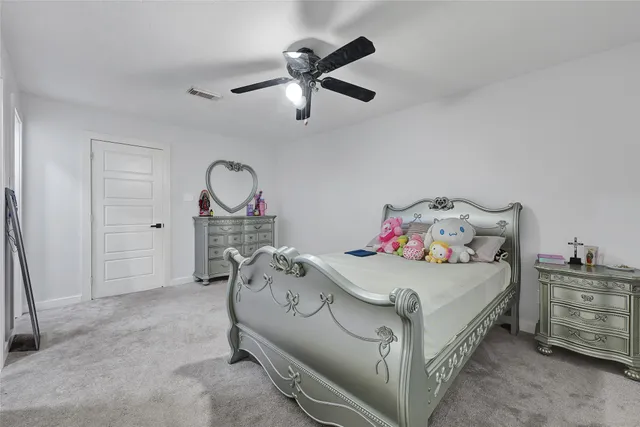 a bedroom with a bed a chandelier and a dresser