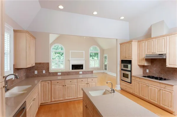 a large kitchen with granite countertop a sink a window stainless steel appliances and white cabinets
