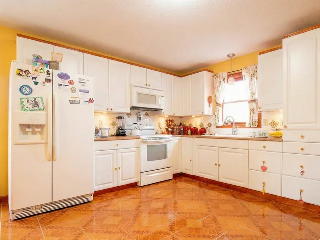 a kitchen with granite countertop white cabinets and white appliances