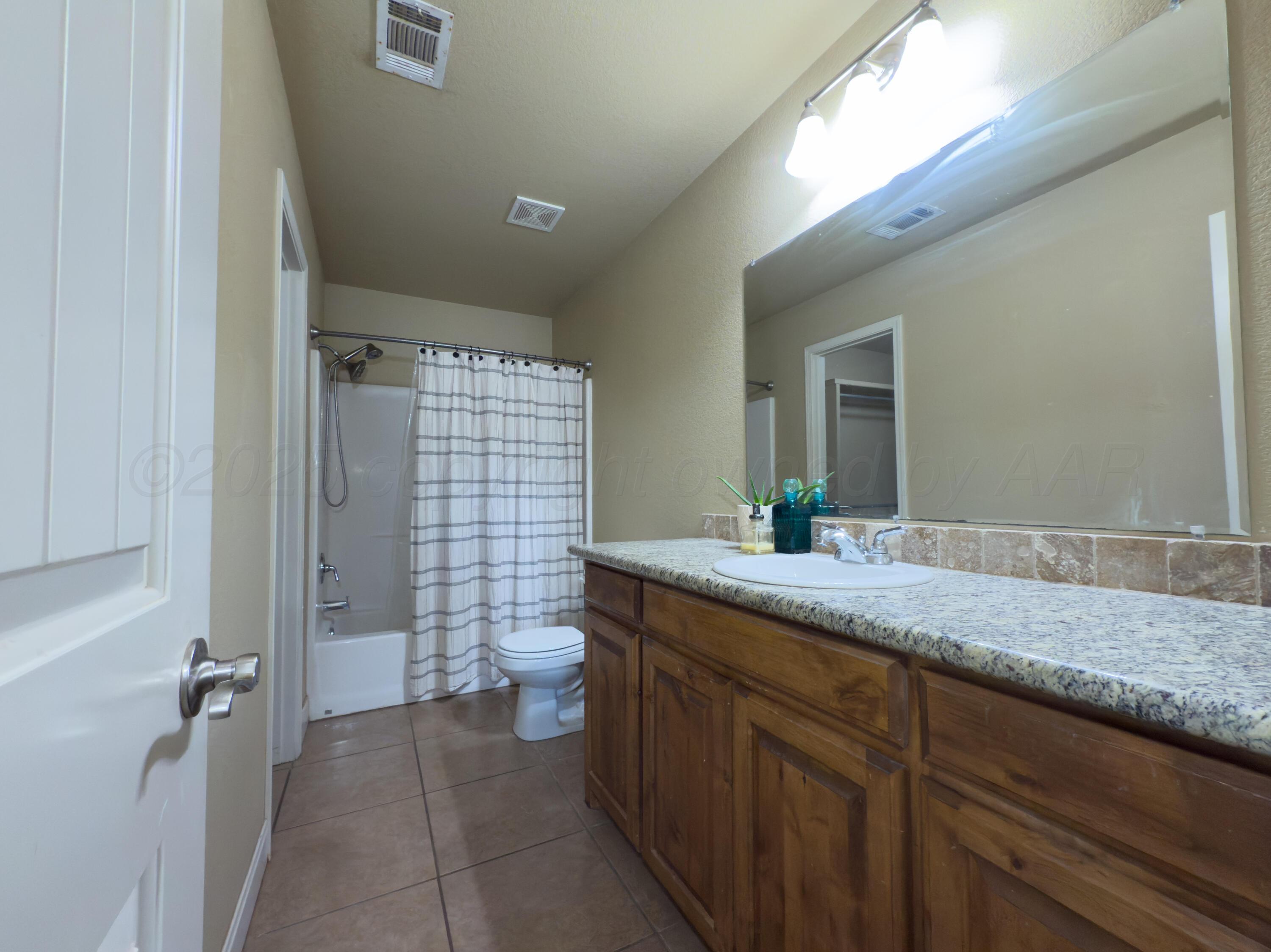 3701 Arden Road Amarillo, TX 79118 - Photo 15 of 18 a bathroom with a granite countertop sink a toilet and shower