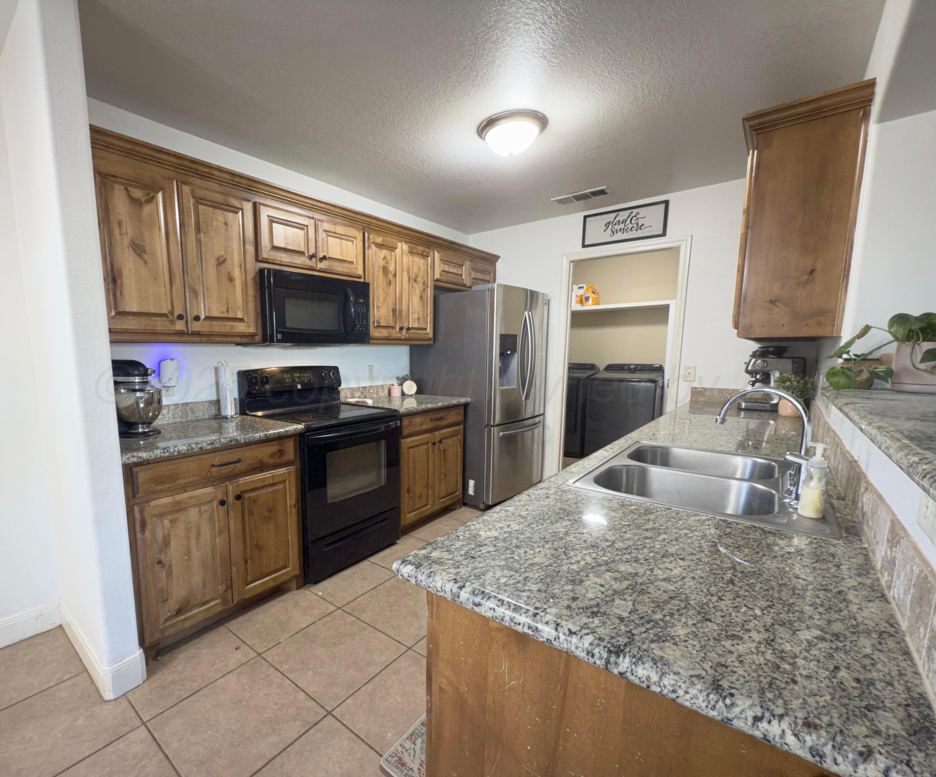3701 Arden Road Amarillo, TX 79118 - Photo 7 of 18 a kitchen with kitchen island granite countertop a sink refrigerator stove microwave and cabinets