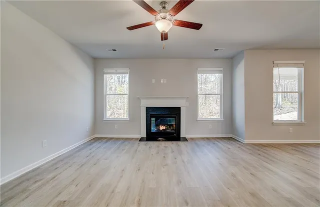 an empty room with windows a fireplace and wooden floor