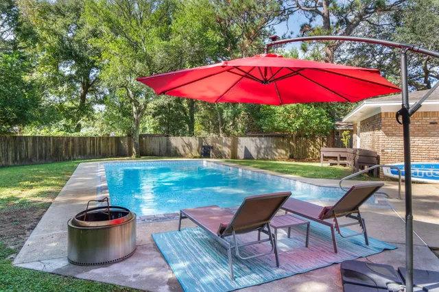 a view of a table and chairs under an umbrella in backyard