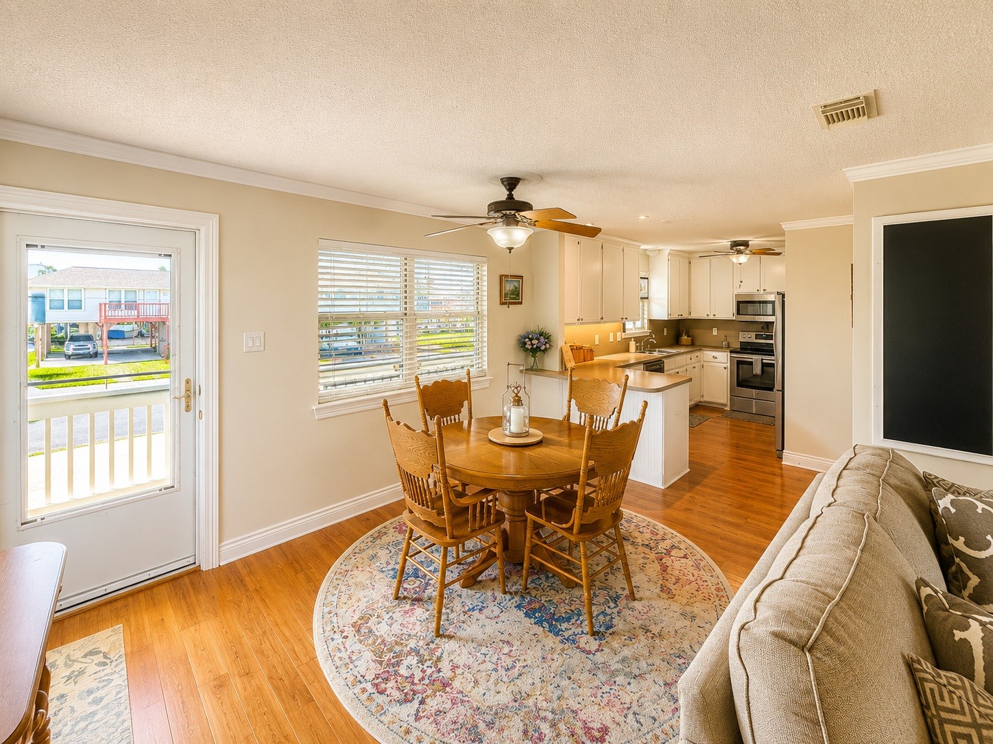135 Sand Shoals Road Freeport, TX 77541 - Photo 20 of 20 This inviting living space features an open floor plan with a cozy dining area, a modern kitchen with white cabinetry and stainless steel appliances, and warm wood flooring throughout. Natural light floods the room through large windows, enhancing the bright and airy ambiance.