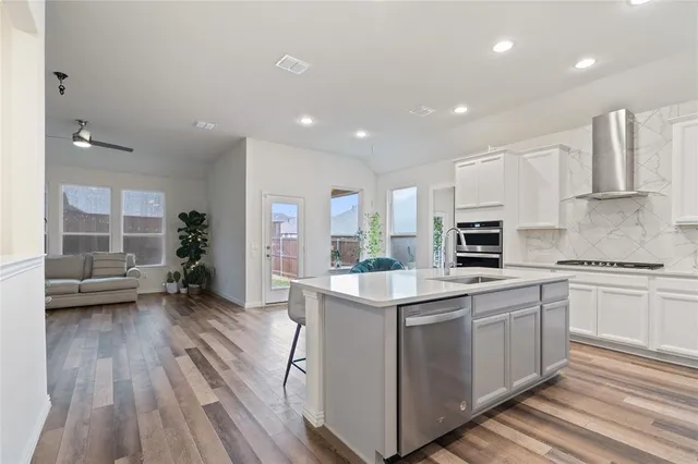 a kitchen with stainless steel appliances a white stove top oven a sink dishwasher and a refrigerator with wooden floor