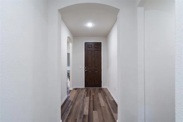a view of a hallway with wooden floor and a bathroom