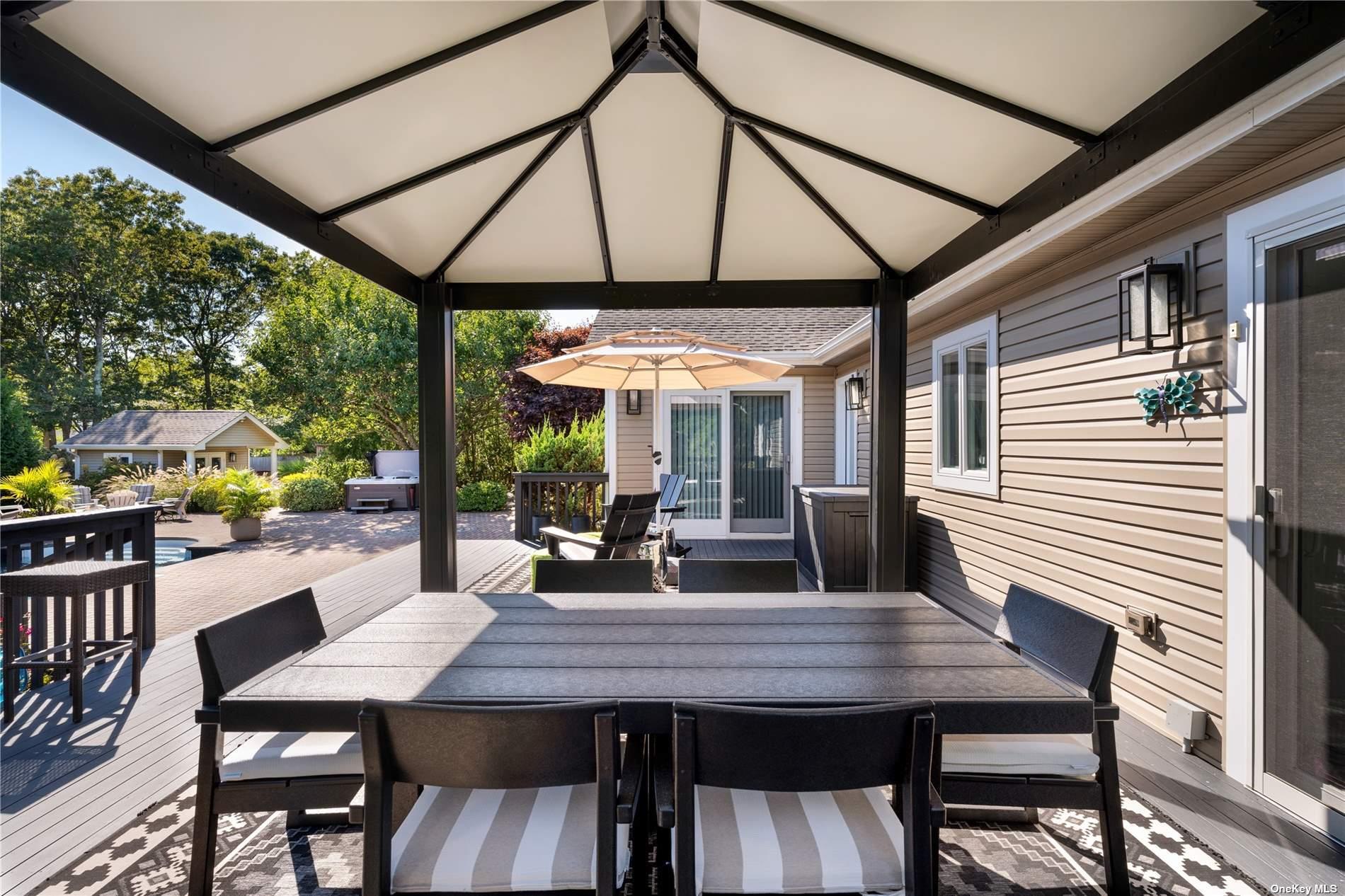 60 Lynncliff Road Hampton Bays, NY 11946 - Photo 11 of 35 a view of a patio with table and chairs under an umbrella