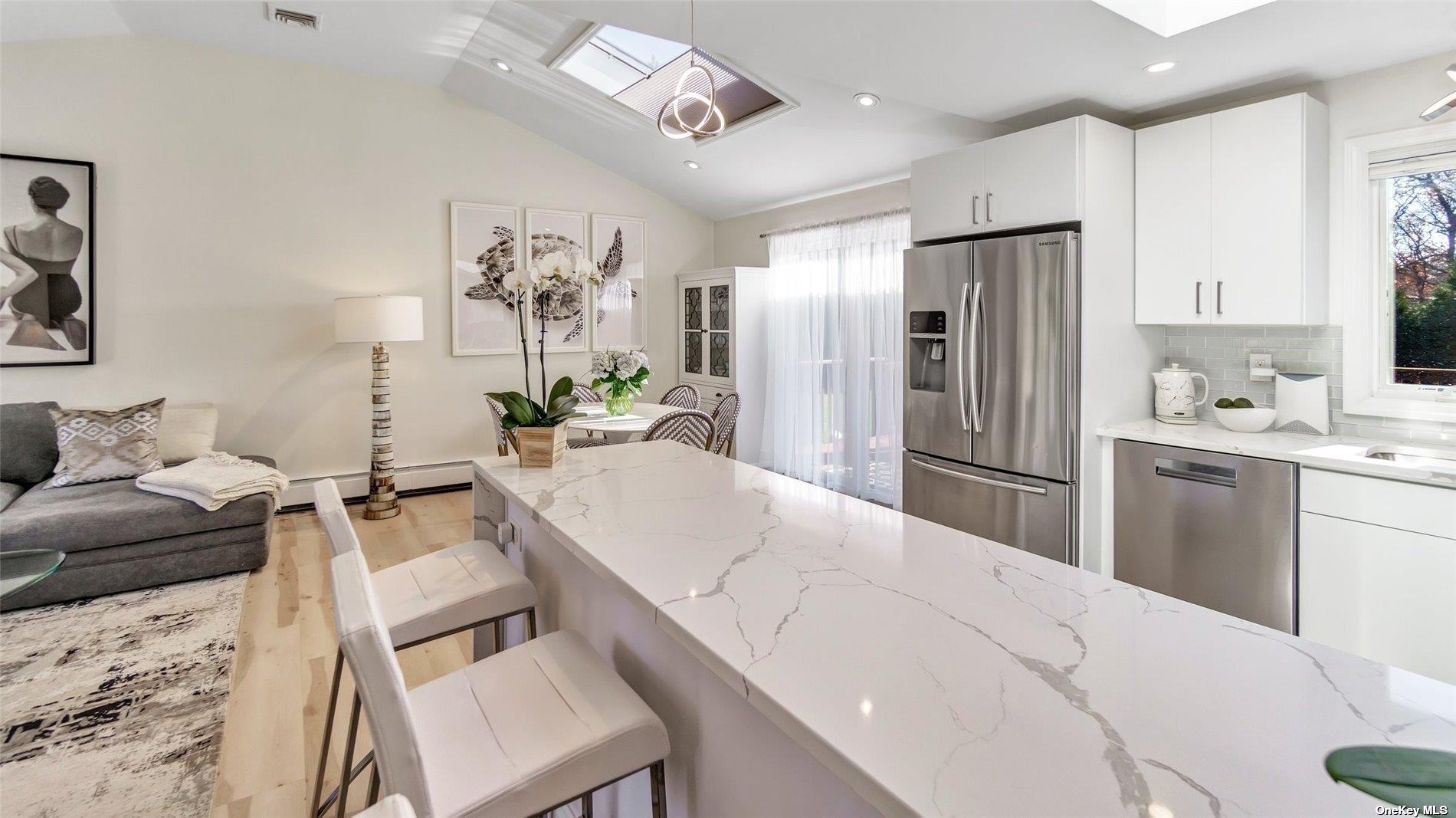 60 Lynncliff Road Hampton Bays, NY 11946 - Photo 25 of 35 a kitchen with stainless steel appliances a refrigerator a sink dishwasher a dining table and chairs with wooden floor