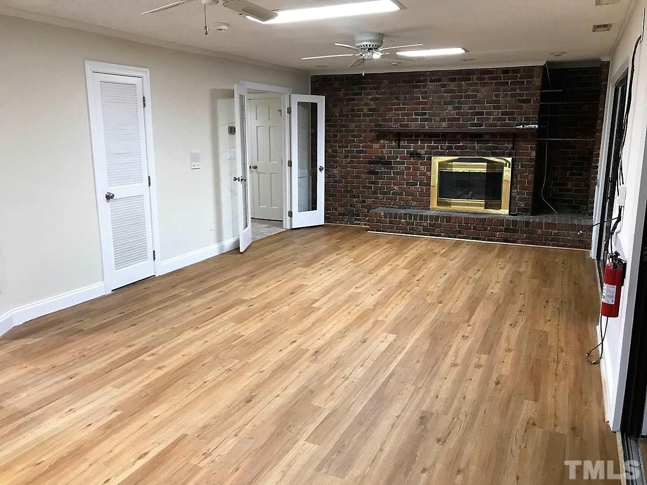 3204 Timberlake Road Raleigh, NC 27604 - Photo 10 of 25 an empty room with wooden floor fireplace and windows