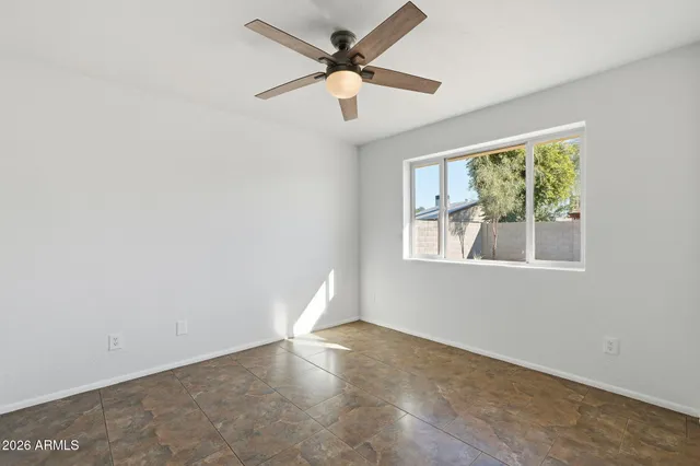 an empty room with windows and ceiling fan