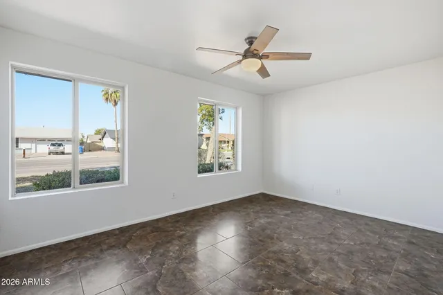 a view of empty room with window and ceiling fan