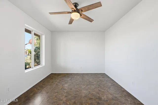 an empty room with windows and fan