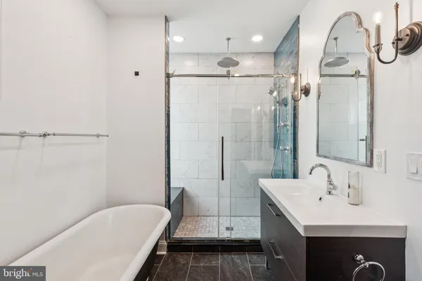 a bathroom with a tub sink shower and mirror