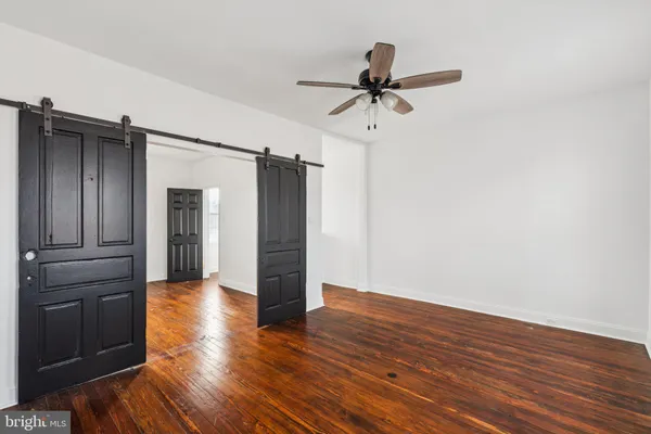 a view of empty room with wooden floor and ceiling fan