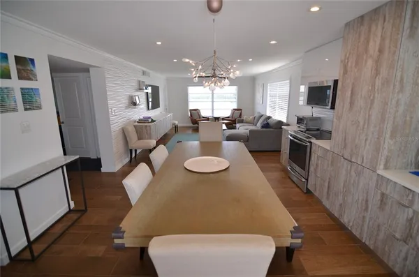 a view of a dining room with furniture a kitchen and chandelier