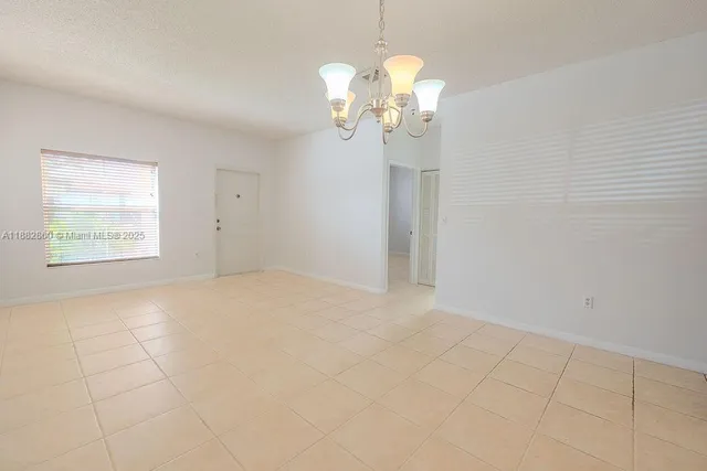 a view of an empty room with a chandelier fan