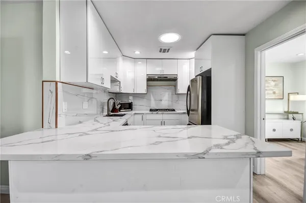 a kitchen with stainless steel appliances kitchen island granite countertop a sink refrigerator and cabinets