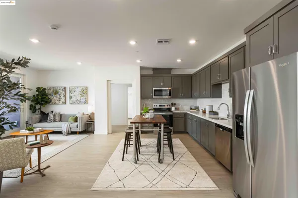 a kitchen with stainless steel appliances kitchen island granite countertop a refrigerator a stove a sink a dining table and chairs with wooden floor