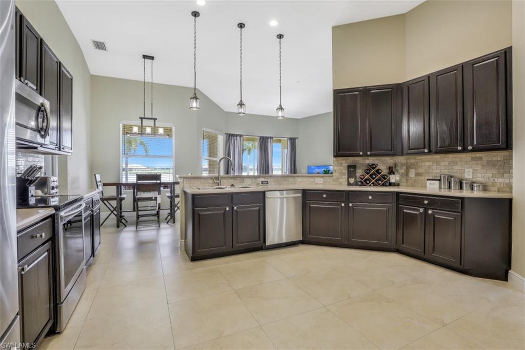 2198 Grove Drive Naples, FL 34120 - Photo 6 of 35 a kitchen with stainless steel appliances kitchen island granite countertop a sink a stove and a refrigerator