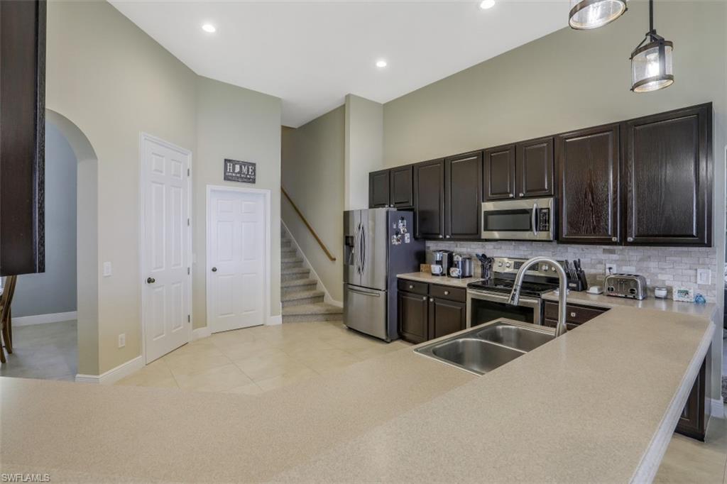 2198 Grove Drive Naples, FL 34120 - Photo 7 of 35 a kitchen with stainless steel appliances microwave stove refrigerator and cabinets