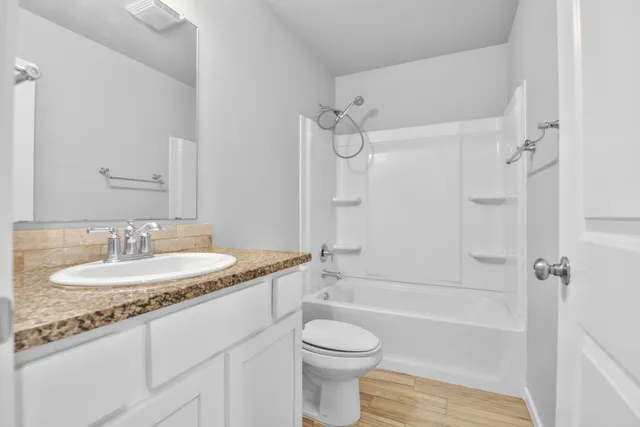 a bathroom with a granite countertop sink toilet mirror and shower