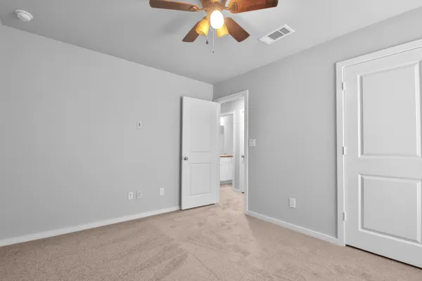 a view of an empty room and chandelier fan