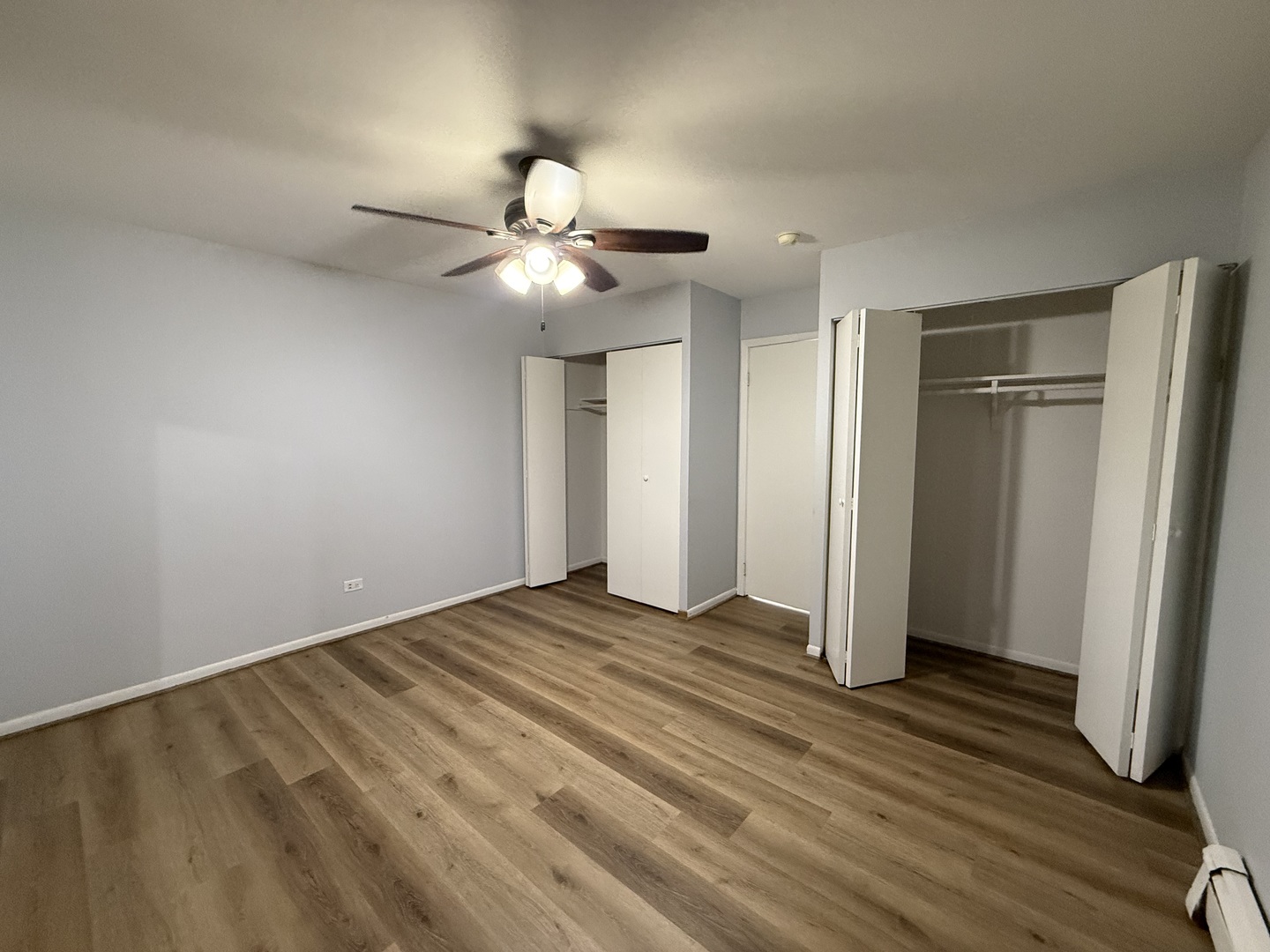 600 Mesa Drive, Unit 104 Hoffman Estates, IL 60169 - Photo 5 of 12 a view of an empty room with wooden floor and a ceiling fan