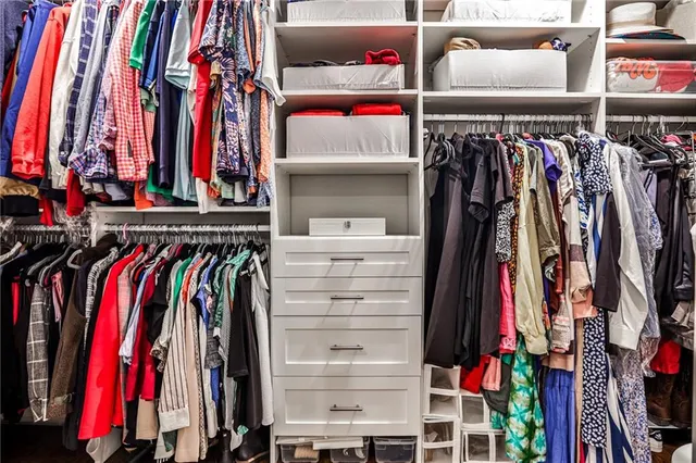 a view of walk in closet with clothes and shoes