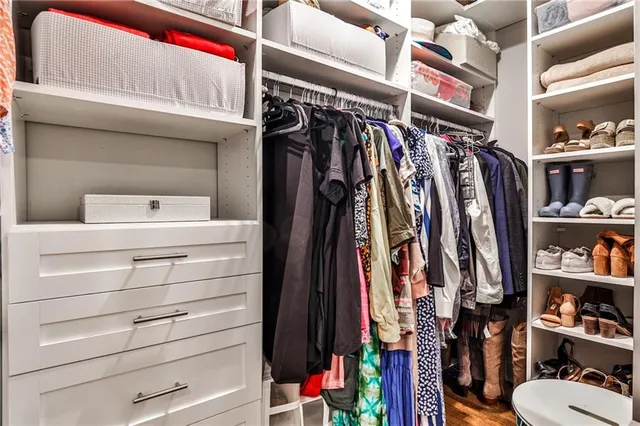 a view of walk in closet with clothes and shoes