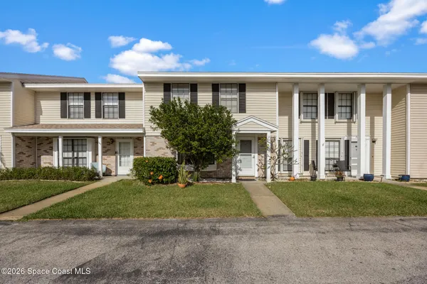 a view of a white house with a yard and plants