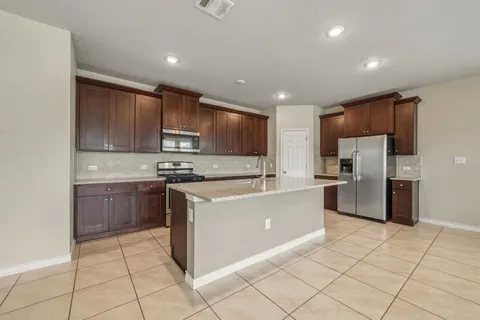 a large kitchen with stainless steel appliances granite countertop a stove a sink and a refrigerator