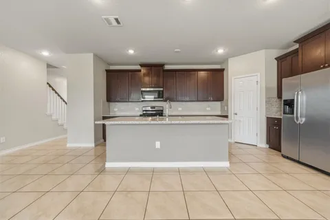 a large kitchen with stainless steel appliances kitchen island granite countertop a refrigerator a stove a microwave and a sink