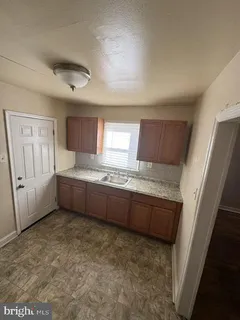 a room with granite countertop a sink and a refrigerator