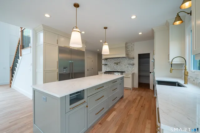a large kitchen with kitchen island a stove a sink a center island and wooden floor