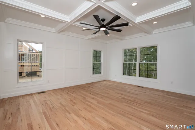an empty room with wooden floor fan and windows
