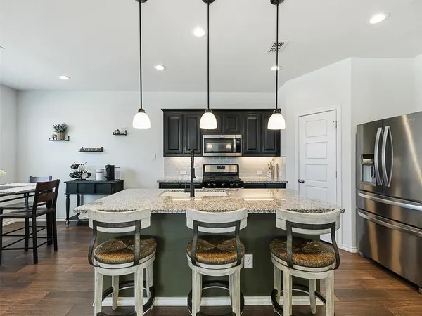a kitchen with a dining table chairs stainless steel appliances and wooden floor
