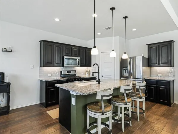 a kitchen with stainless steel appliances kitchen island granite countertop a stove a refrigerator a oven a sink with a dining table and chairs